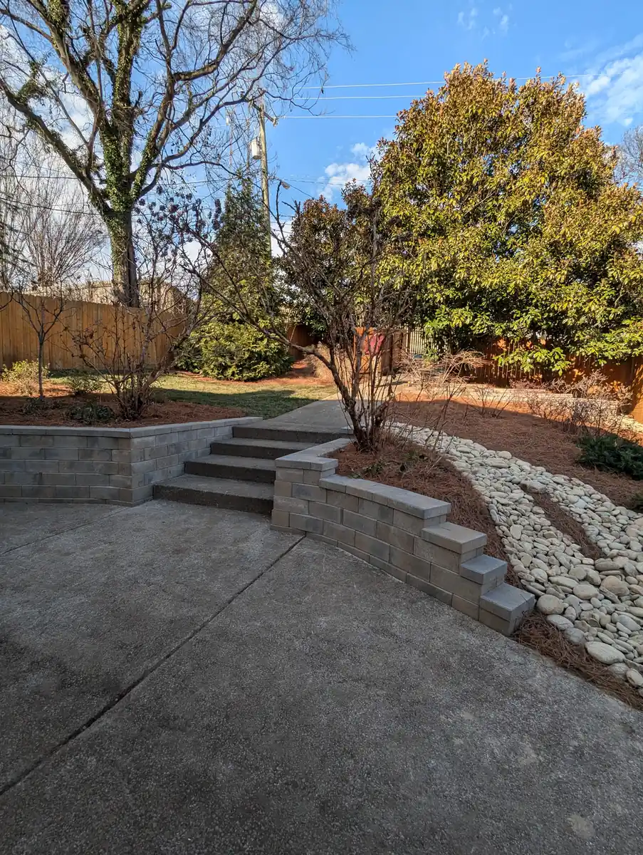 Block retaining wall with steps beside a concrete driveway at a brick home in Nashville, TN