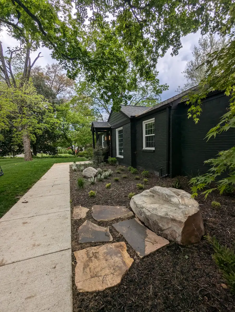 Boulder and flagstone accent beside a concrete walkway at a black cottage in Nashville, TN