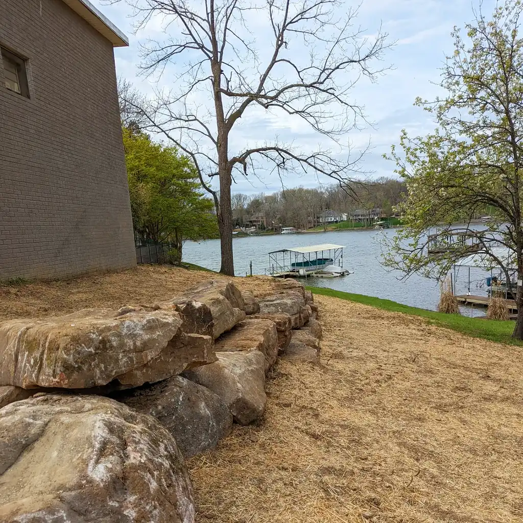 Boulder retaining wall beside a brick home on a lakefront lot in Middle Tennessee