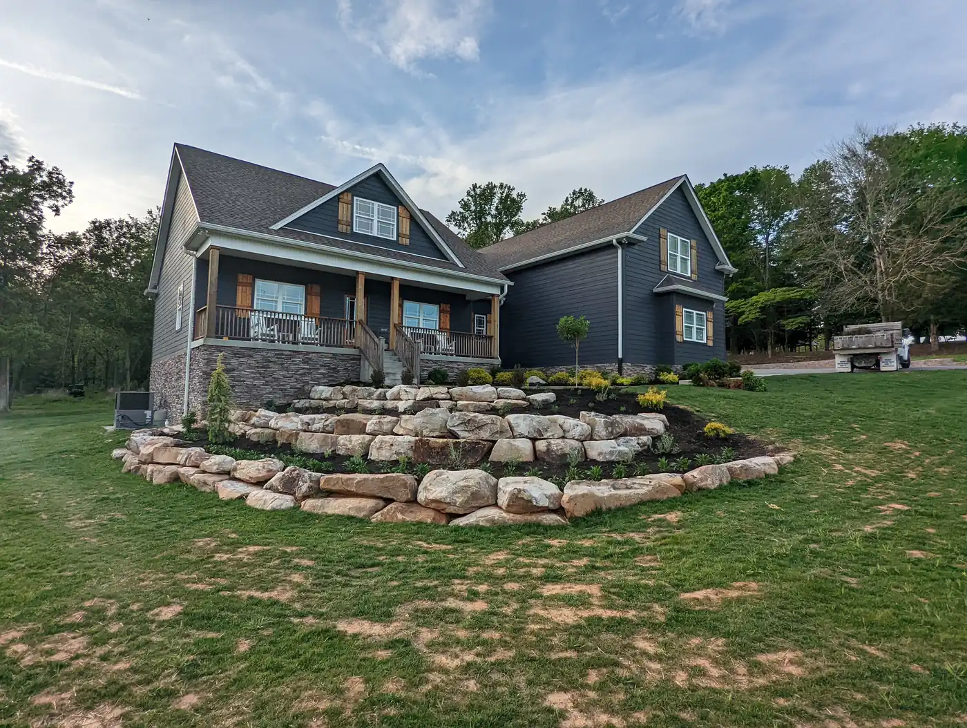 Boulder terrace retaining walls in the front yard of a blue craftsman home in Nashville, TN