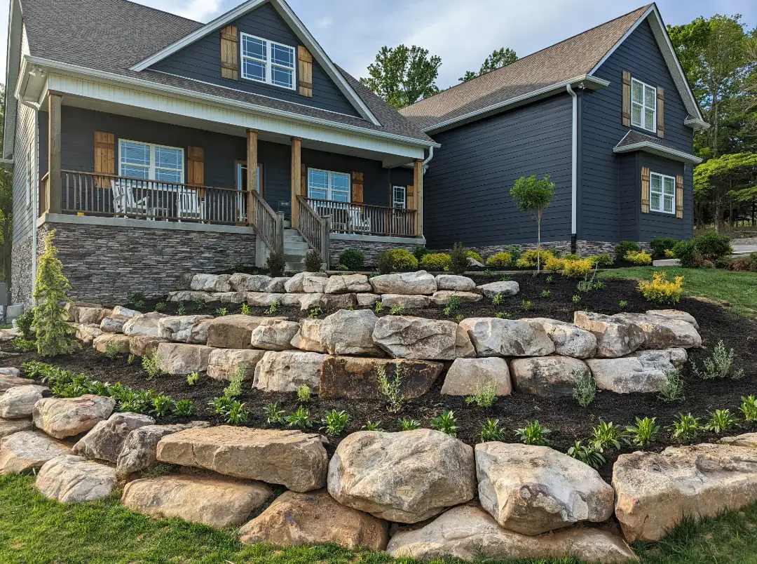 Boulder terrace walls and new plantings in front of a blue craftsman home in Nashville, TN