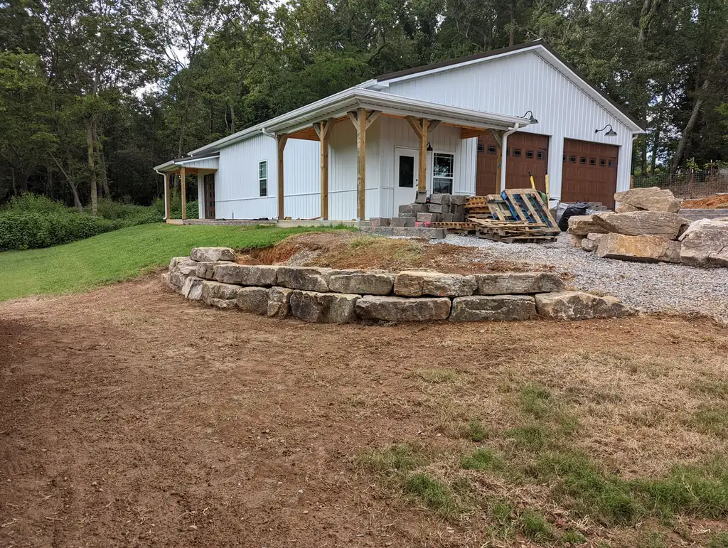 Boulder wall bordering a gravel pad at a white barn shop in Middle Tennessee