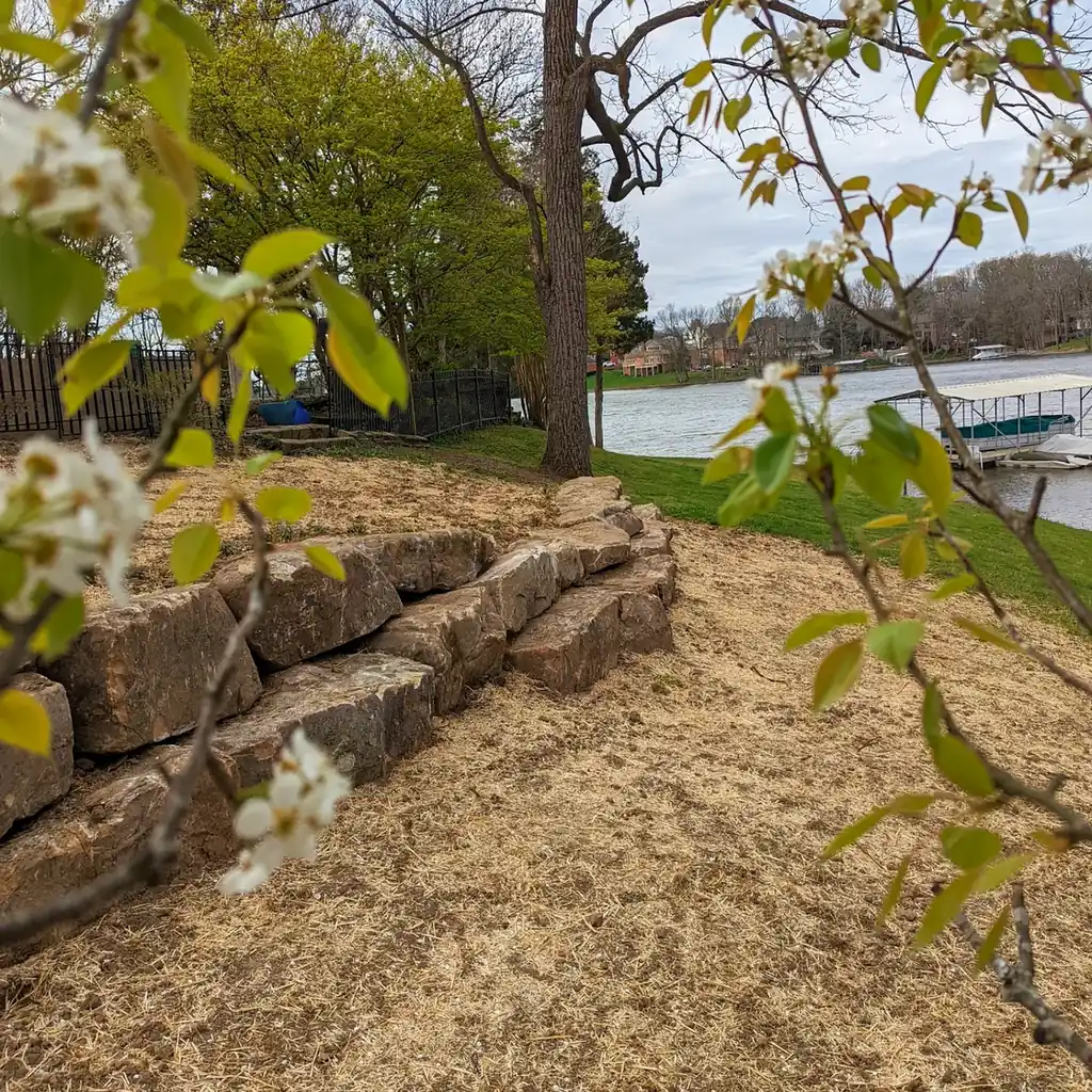 Boulder retaining wall with spring blossoms overlooking a lake and dock in Middle Tennessee