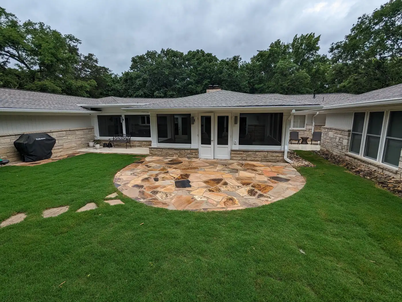 Circular flagstone patio and stepping stones behind a stone ranch home in Nashville, TN