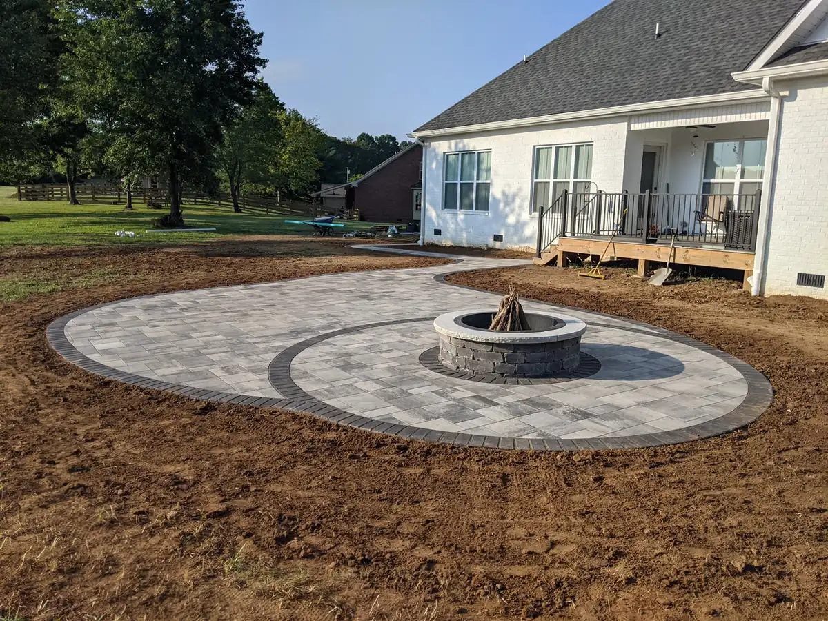 Circular paver patio with fire pit and walkway behind a white home in Nashville, TN