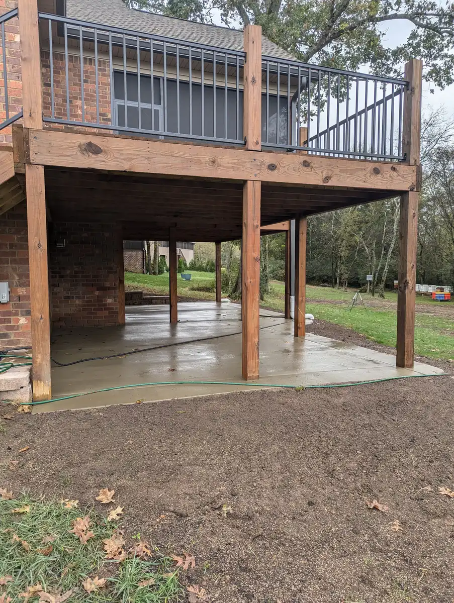 Finished concrete patio under an elevated wood deck overlooking a lawn in Nashville, TN
