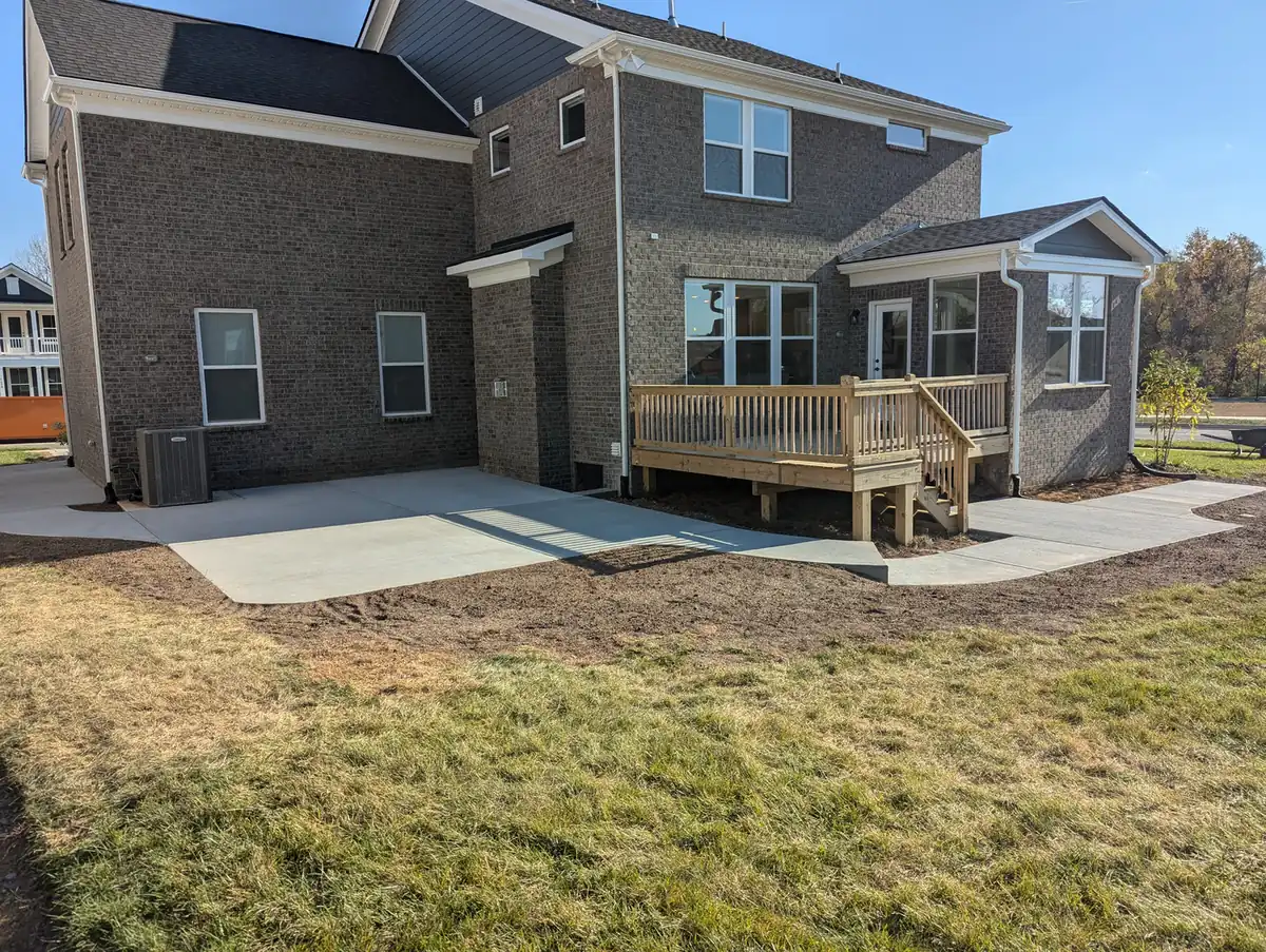 New concrete patio beside a wood deck at the back of a brick two-story home in Nashville, TN