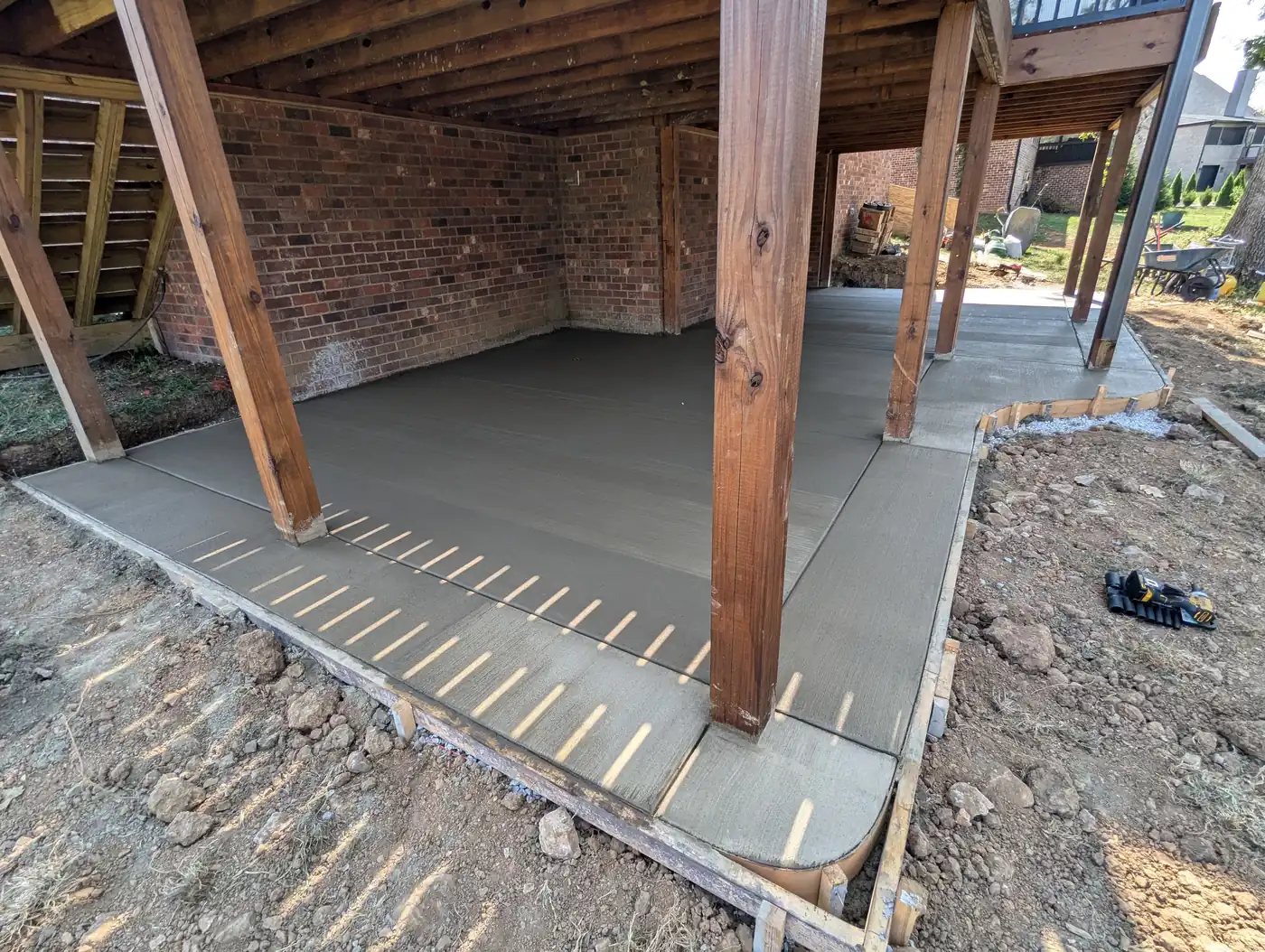 Concrete patio poured beneath an elevated deck at a brick home in Nashville, TN