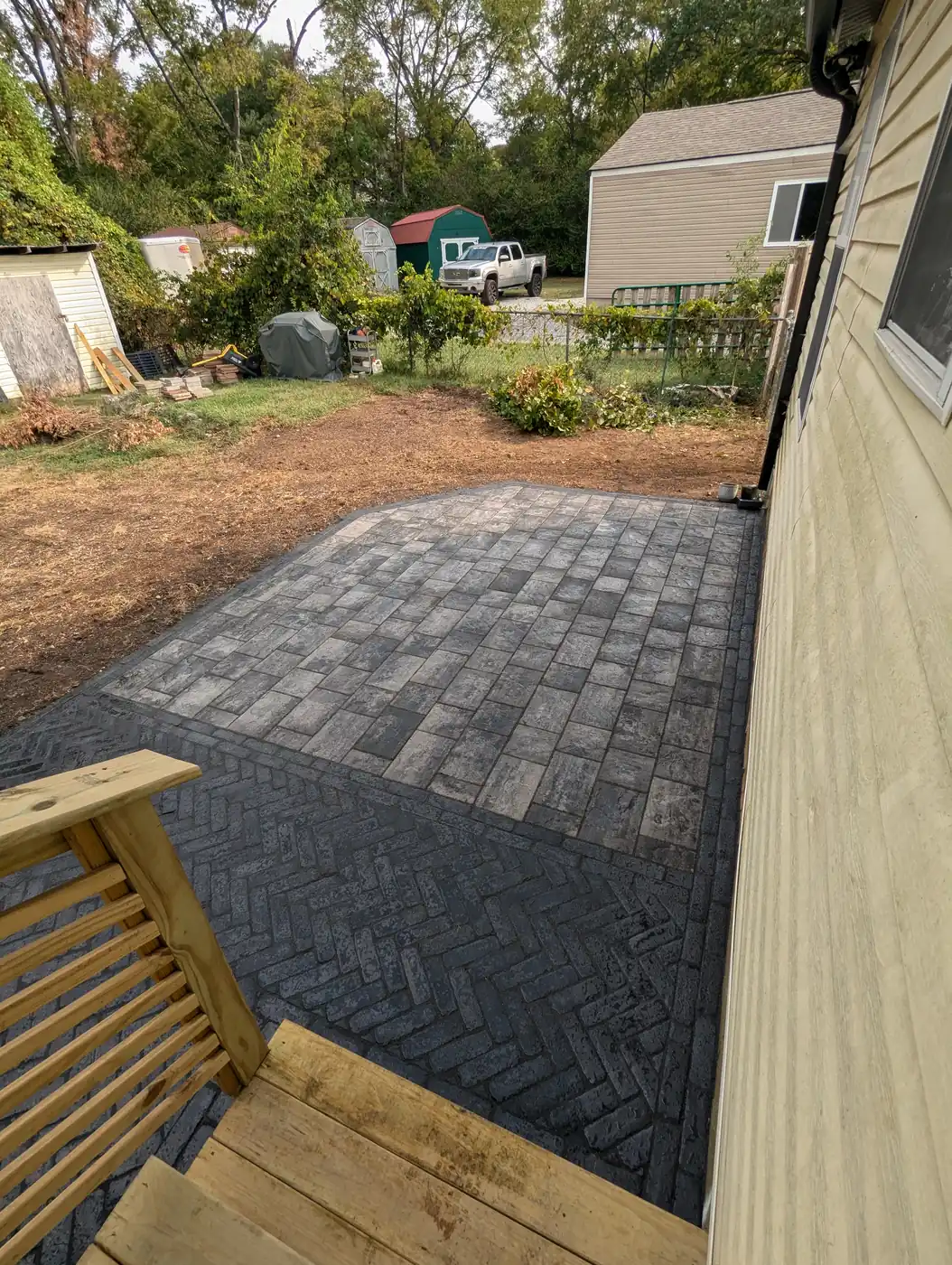 Curved-edge paver patio beside a home with a backyard shed in Nashville, TN