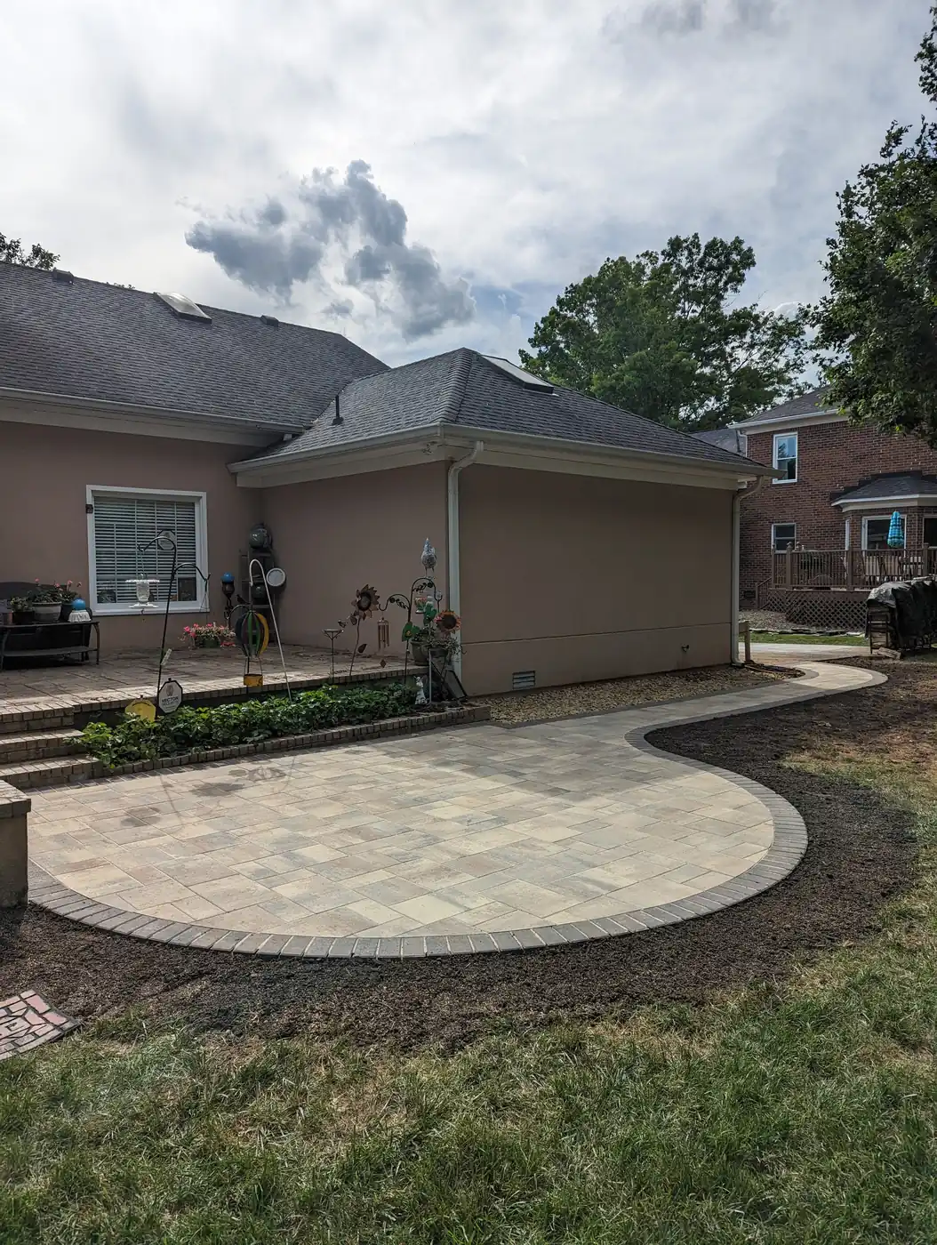 Curved paver patio with a dark border behind a tan stucco home in Nashville, TN