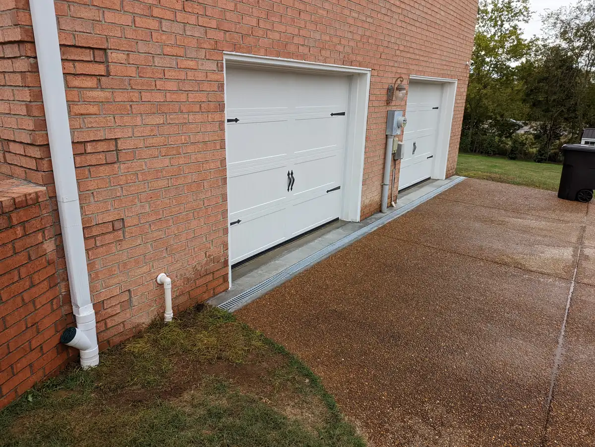 Downspout tied into a buried drain line at a brick garage in Nashville, TN