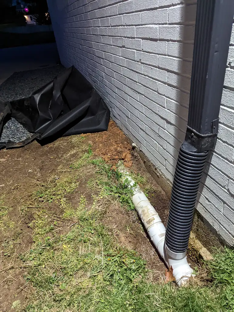 Corrugated downspout drain connection with gravel and filter fabric at a foundation in Nashville, TN