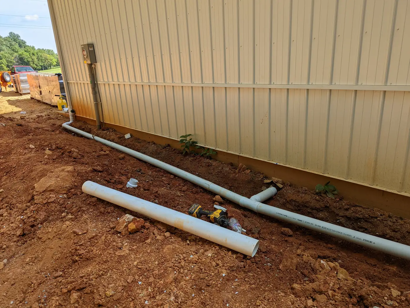 Downspout drain lines being routed along a metal building foundation in Nashville, TN