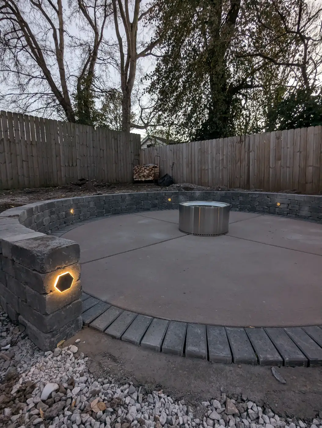 Round fire pit patio with seat wall lights at dusk in Nashville, TN
