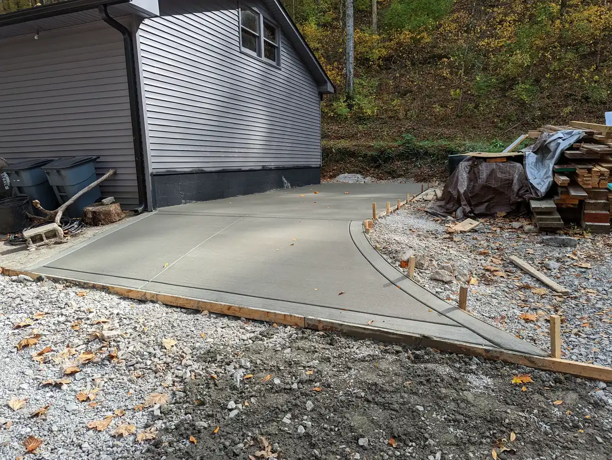 Freshly poured concrete driveway pad in wood forms beside a gray home in Nashville, TN