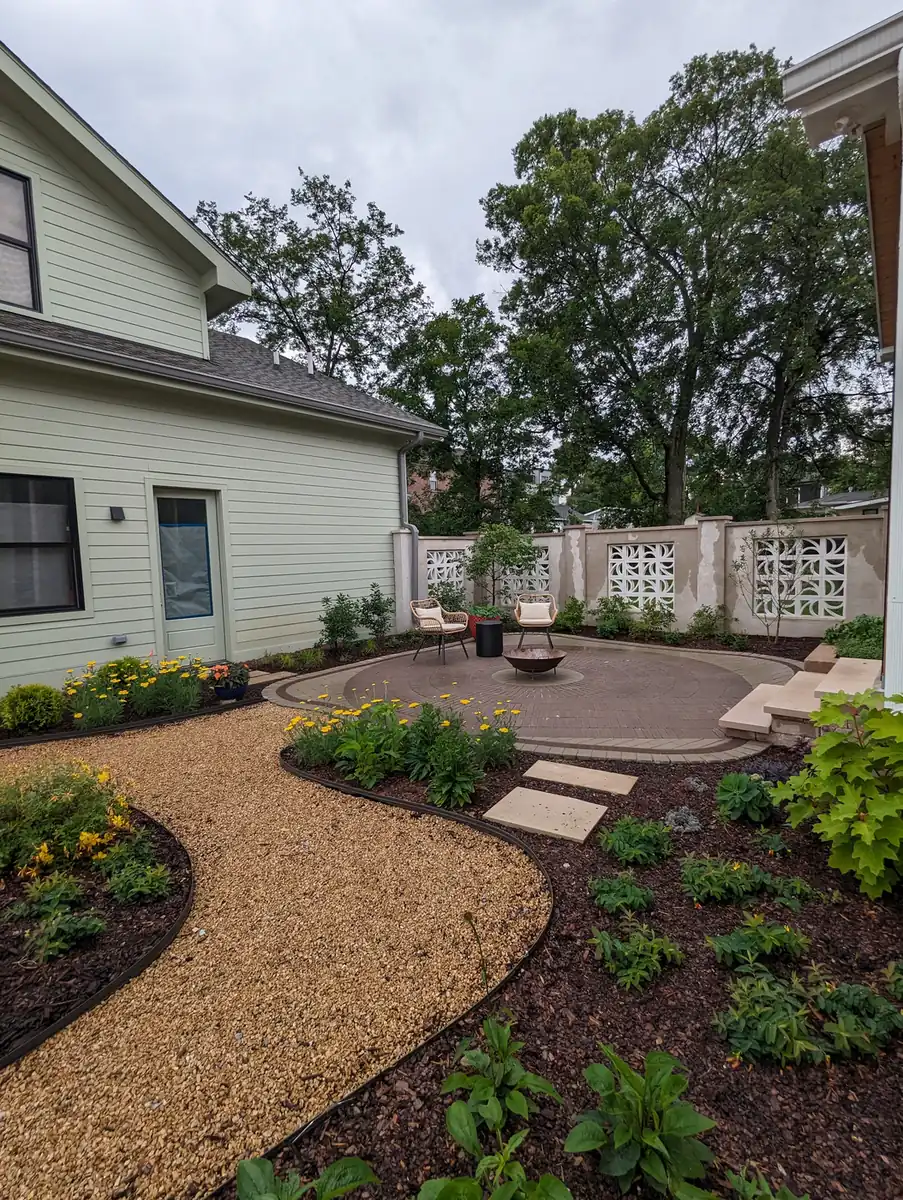 Pea gravel garden path winding through new planted beds behind a white home in Nashville, TN