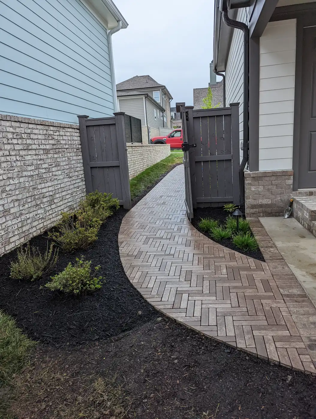 Curved herringbone paver walkway with new plantings along a side yard in Nashville, TN