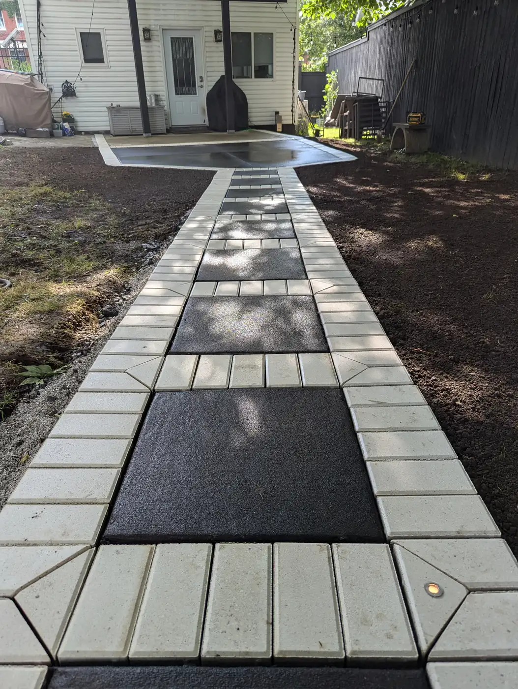 Modern side-yard walkway of large light concrete pavers with dark inset panels in Nashville, TN