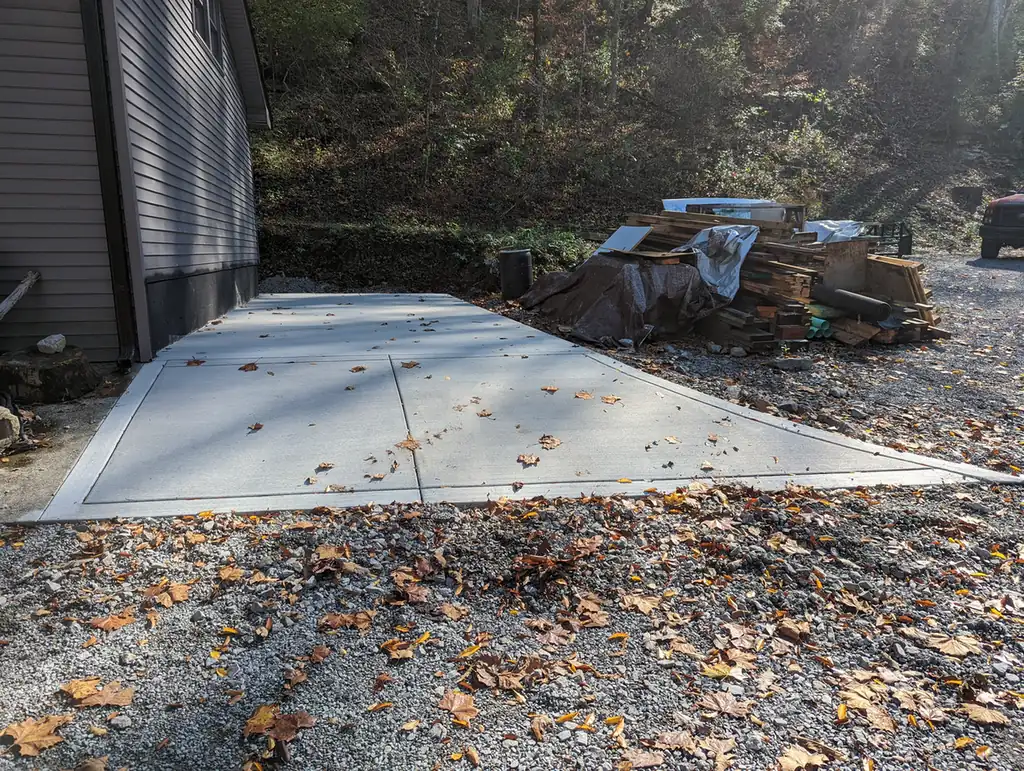 New concrete driveway pad and gravel apron behind a gray house in Nashville, TN