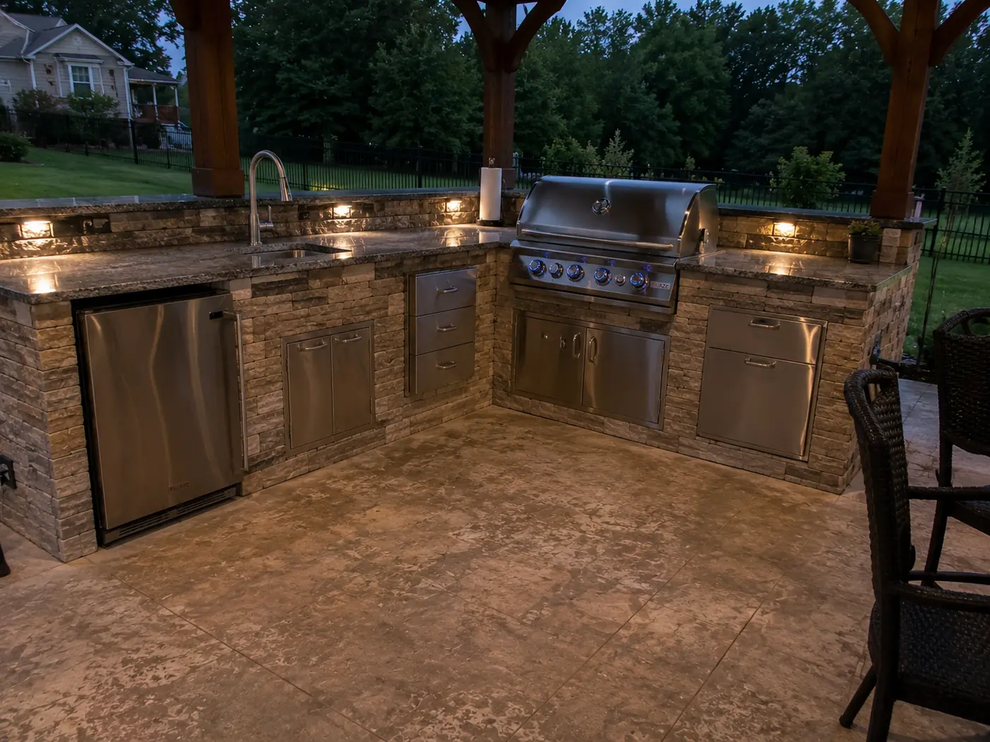 Outdoor kitchen with stainless appliances under a pergola at dusk in Nashville, TN