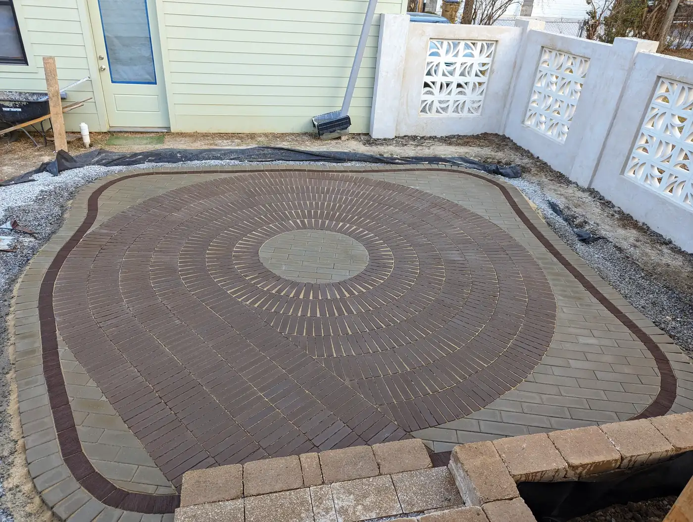 Oval paver patio with a circle kit center and dark border under construction in Nashville, TN