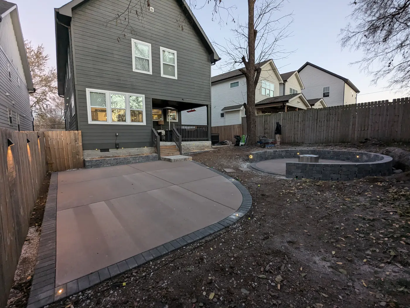 Concrete patio with paver border and in-ground lights behind a modern gray home in Nashville, TN