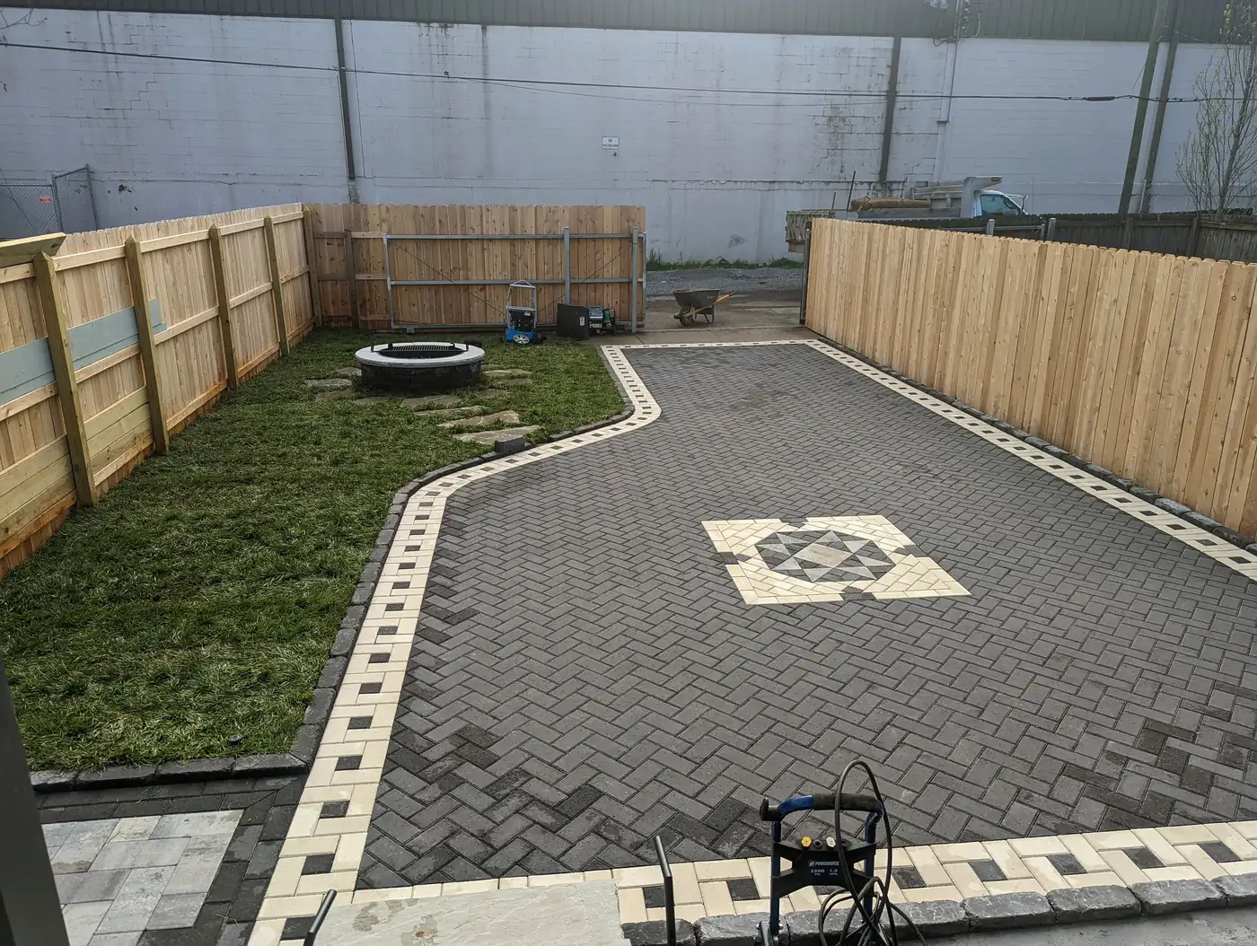 Paver patio with a decorative center inlay and light border beside new sod in Nashville, TN
