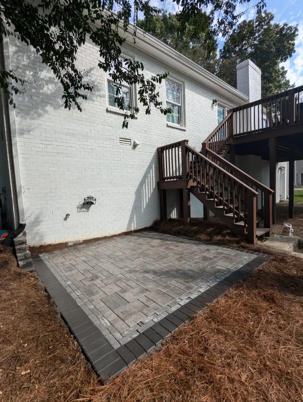 Paver patio at the foot of deck stairs at a white brick home in Nashville, TN