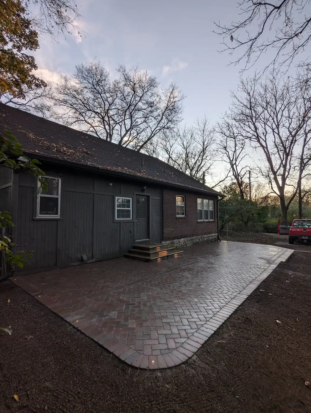 Paver patio at dusk beside a dark-sided home with pergola in Nashville, TN