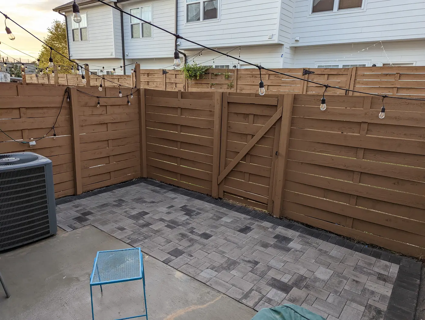 Paver patio in a fenced side yard with a wood gate and string lights in Nashville, TN