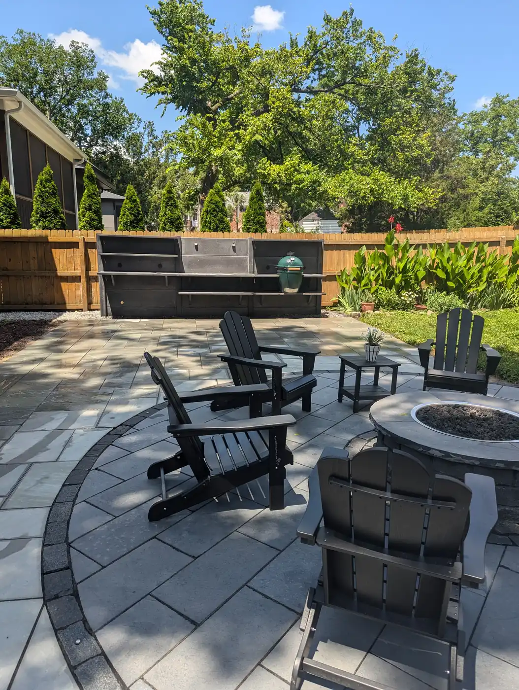 Paver patio with fire pit, black chairs and an outdoor grill station on a sunny day in Nashville, TN