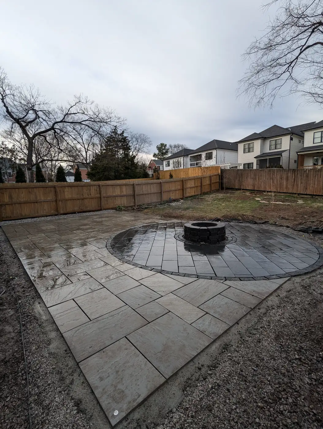 Paver patio with fire pit beside a wood fence on an overcast day in Nashville, TN