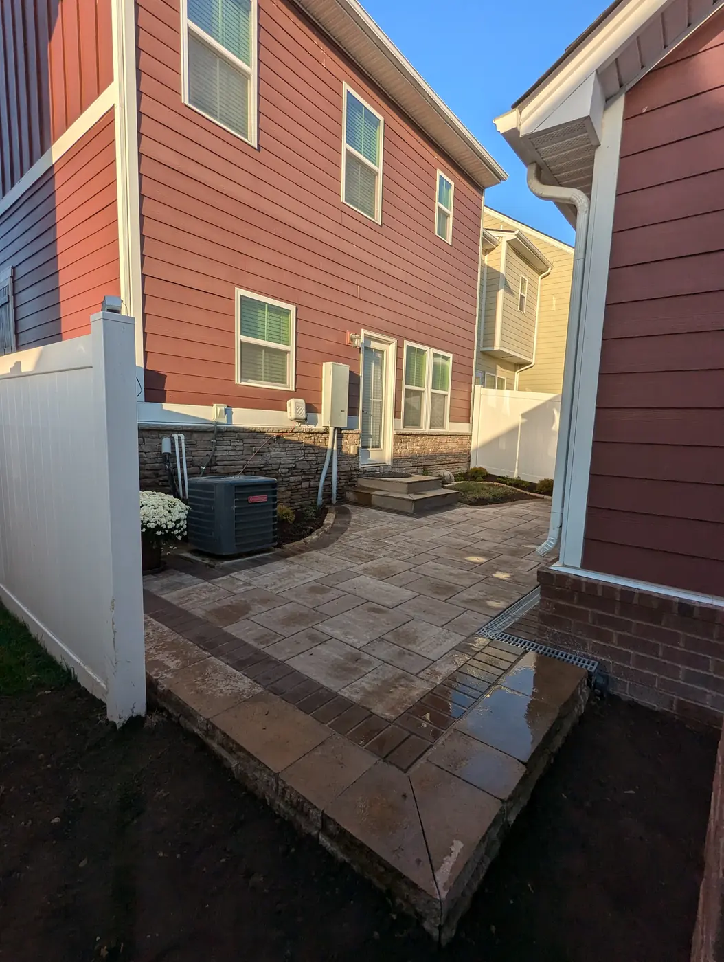 Paver patio in a narrow side yard between a red and a white home in Nashville, TN