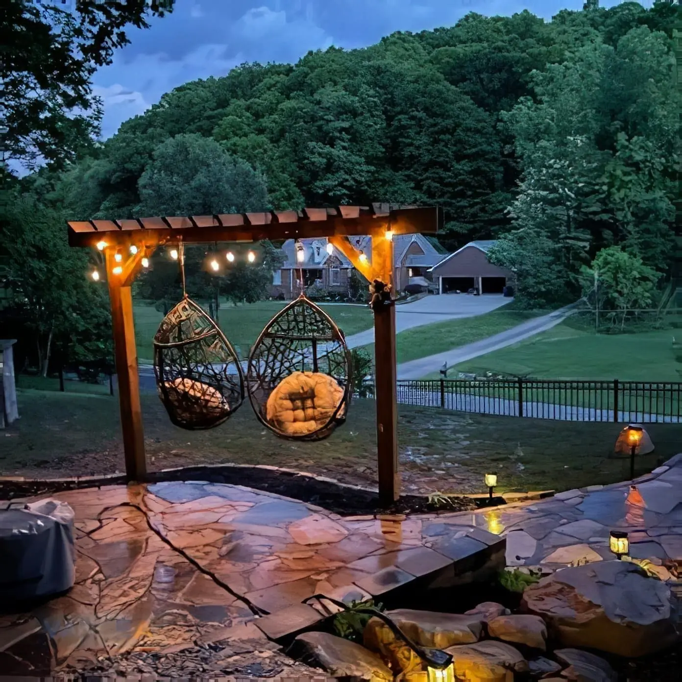 Pergola with string lights and hanging egg chairs over a flagstone patio at dusk in Nashville, TN