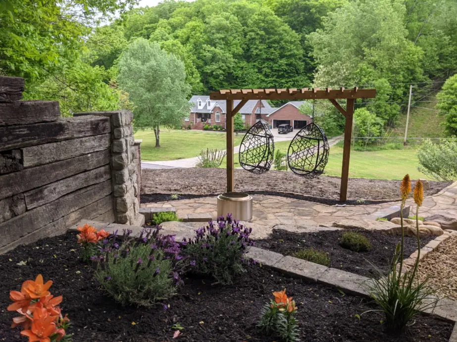 Planted bed of lilies and lavender against a timber wall with a pergola swing behind in Nashville, TN