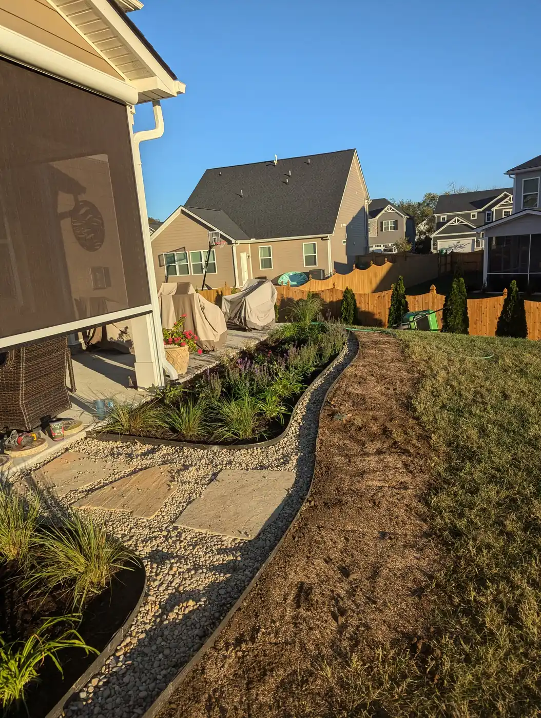Planted border of grasses and shrubs with rock edging along a home in Nashville, TN