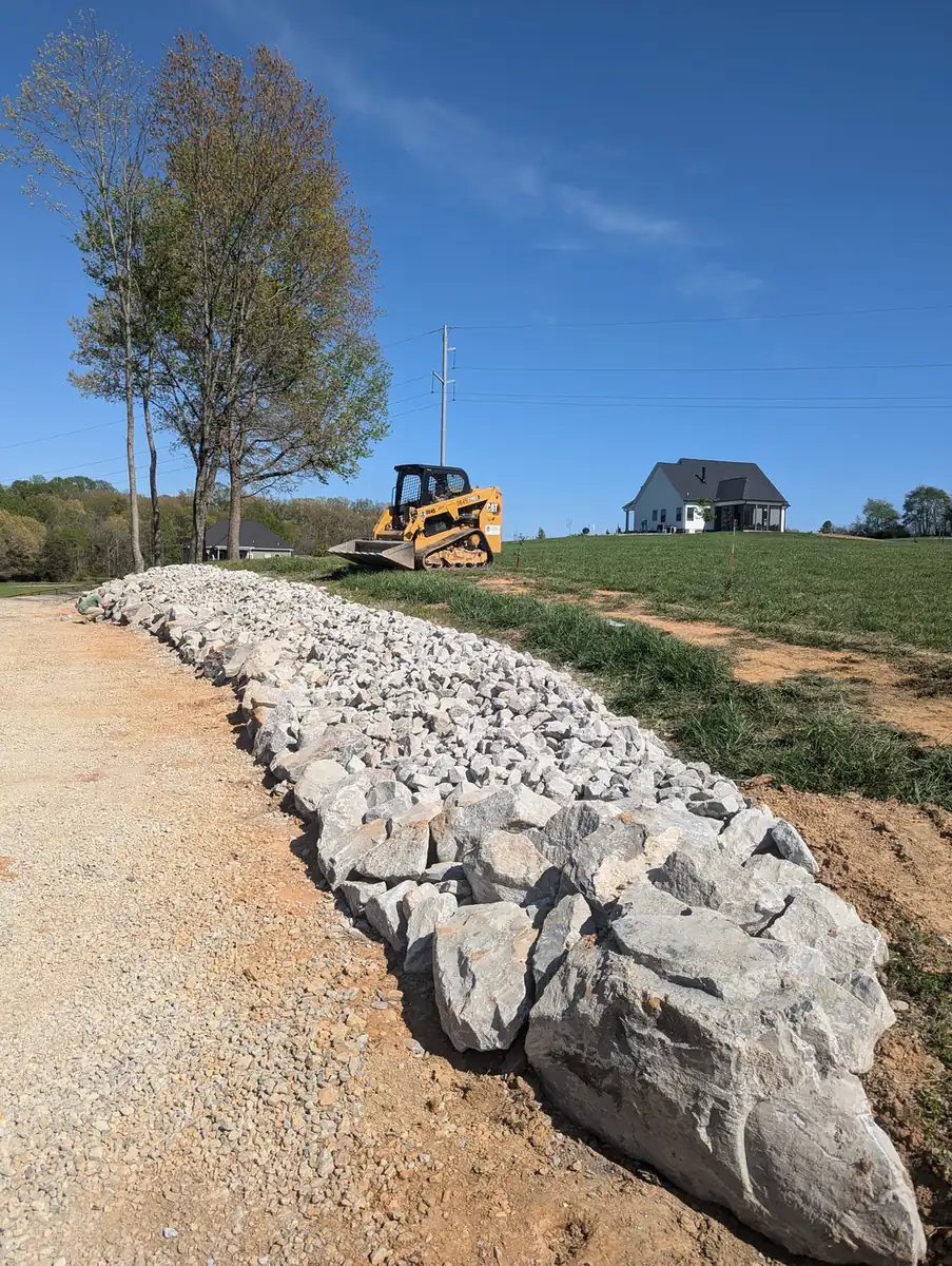 Riprap rock drainage swale built along a gravel drive to control runoff in Middle Tennessee