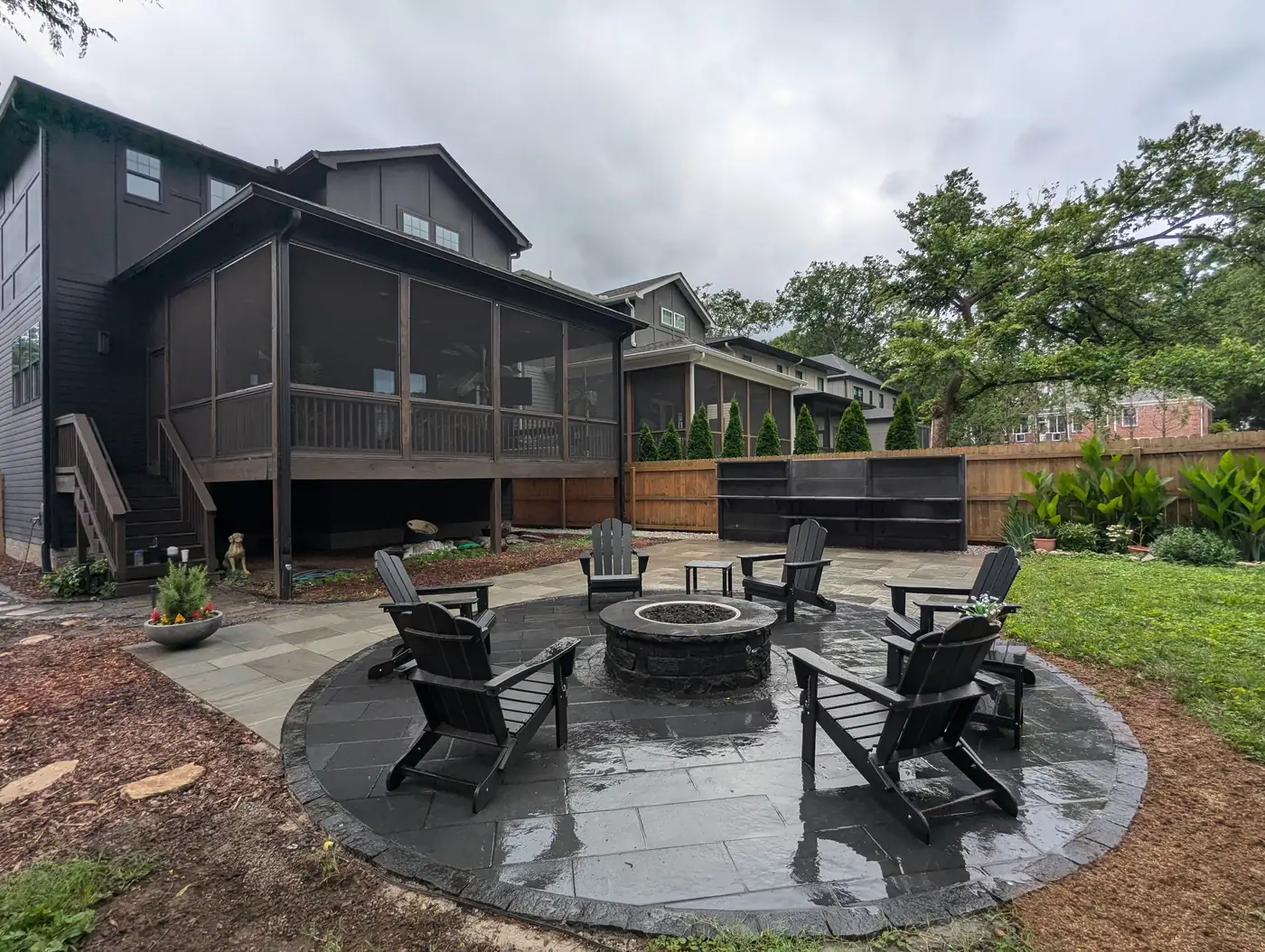 Round paver fire pit patio with black chairs behind a dark modern home in Nashville, TN
