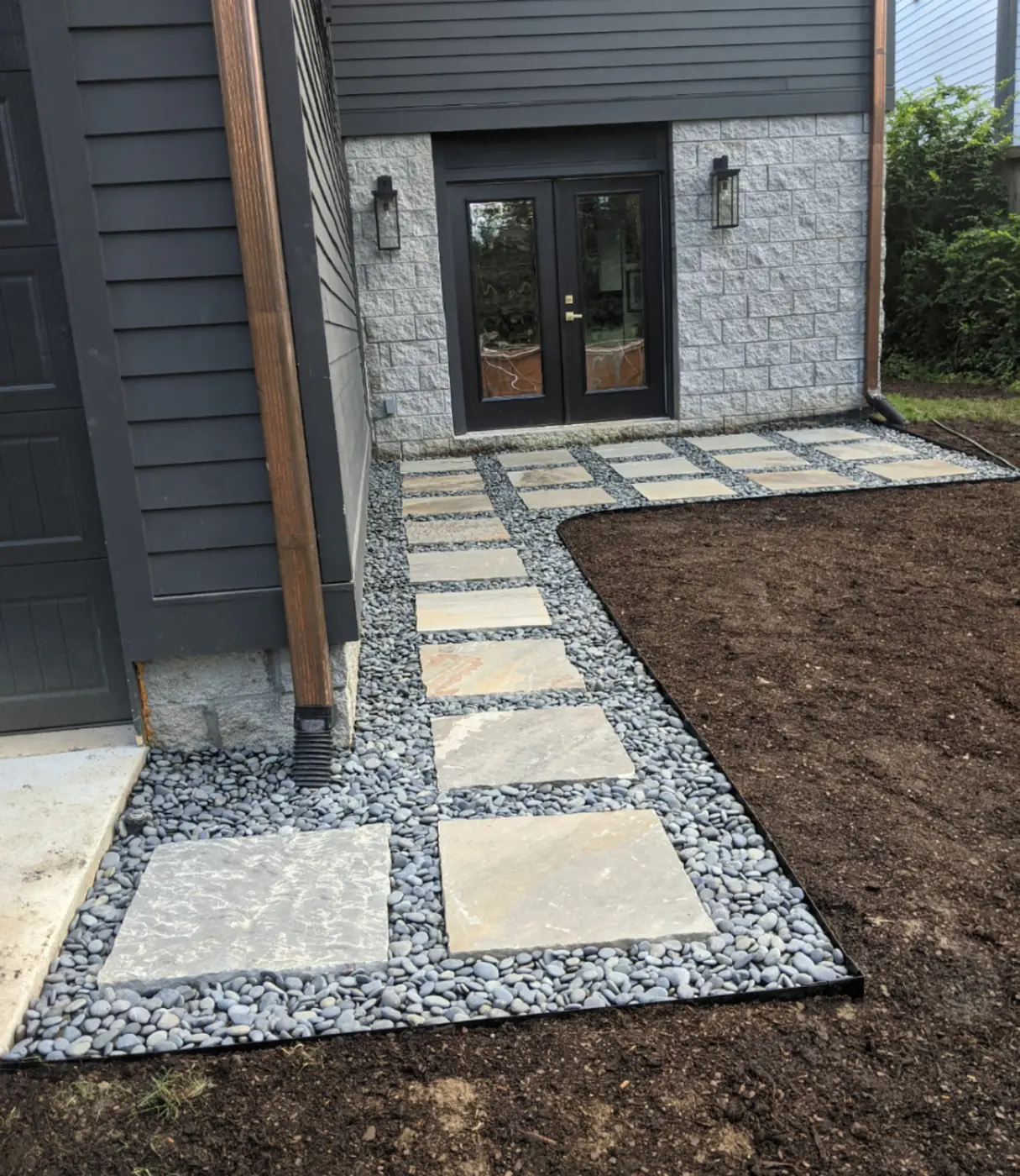 Square stepping pavers set in gravel at a modern black-door entry in Nashville, TN