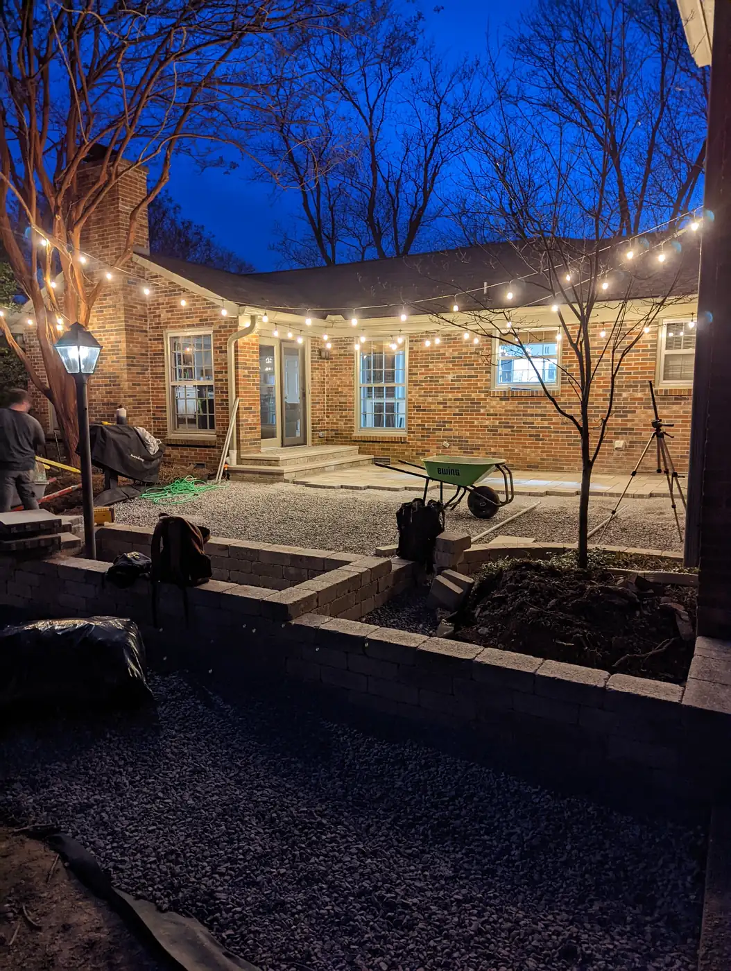 String lights and a lamp post over a backyard patio at a brick home at dusk in Nashville, TN