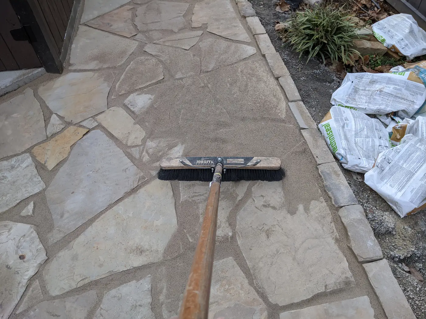 Sweeping polymeric sand into the joints of a new flagstone patio in Nashville, TN
