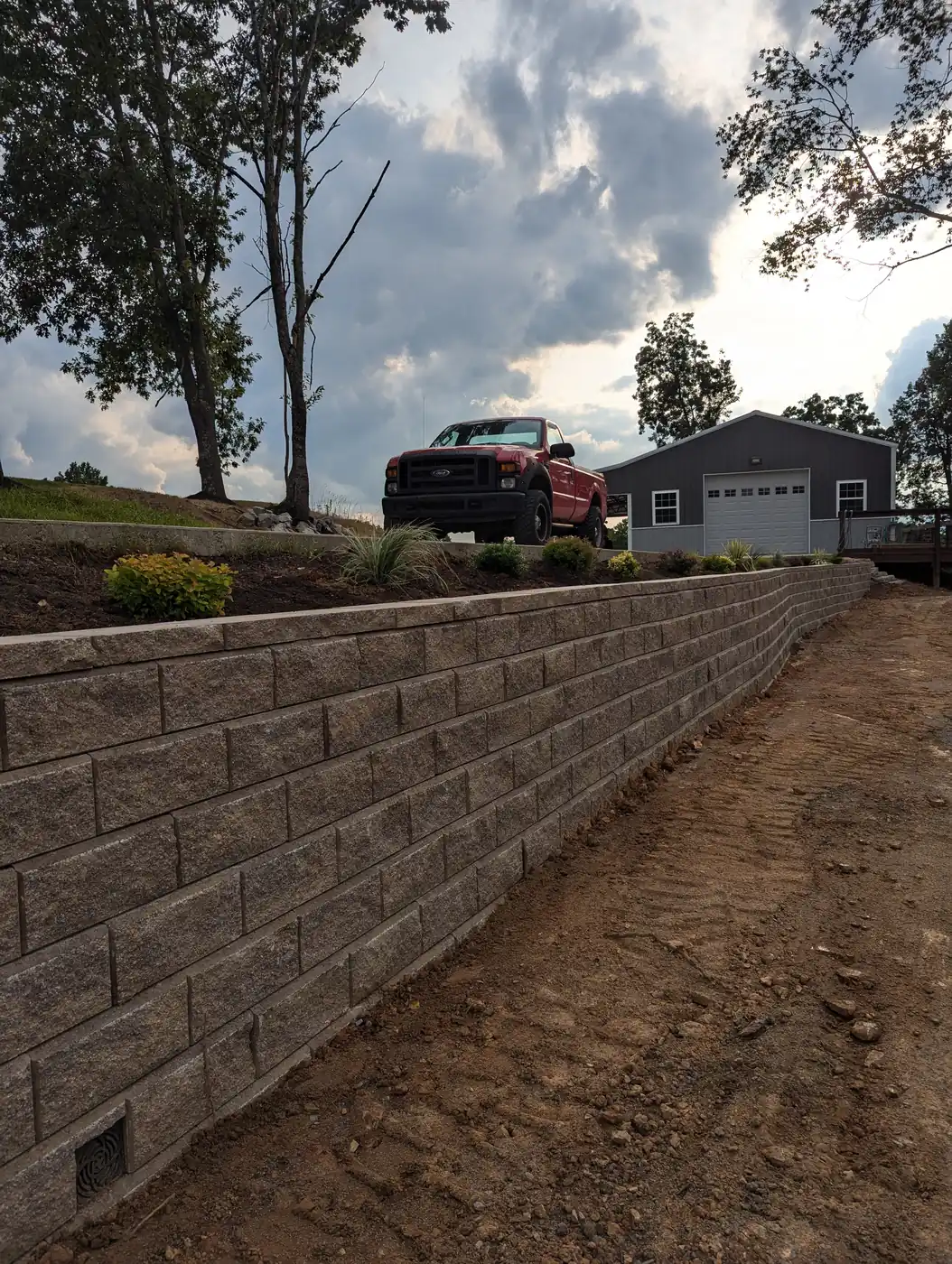 Tall block retaining wall holding a driveway bank beside a shop in Nashville, TN