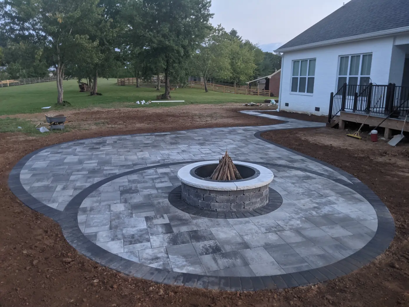 Two-tier circular paver patio with a stone fire pit behind a white home in Nashville, TN