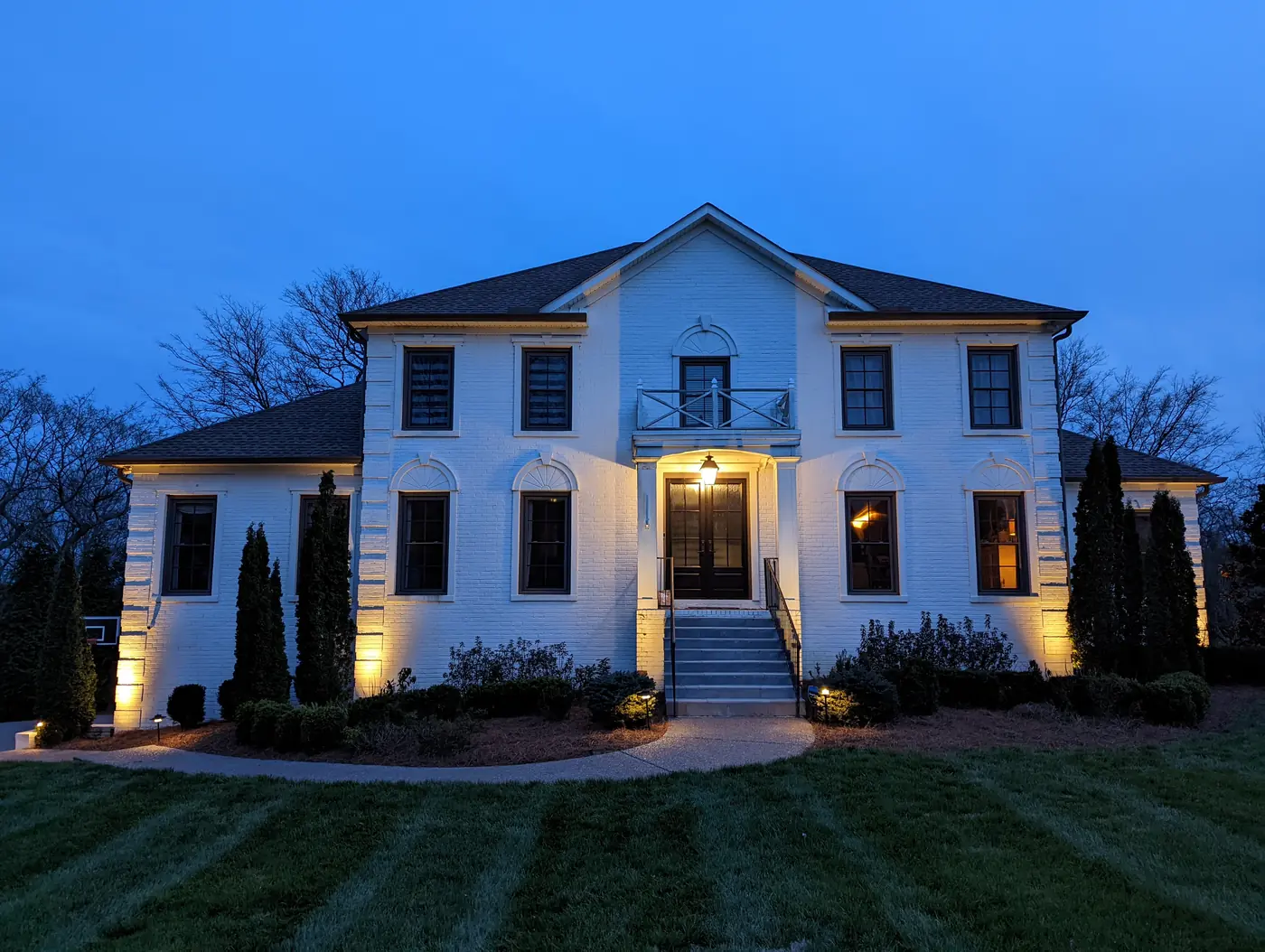 Architectural uplighting on a white colonial home at night in Nashville, TN